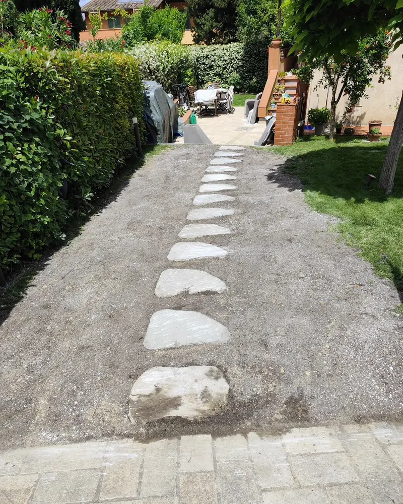 Camminamento di lastre di pietra su terra appena sistemata, tra una siepe e il prato